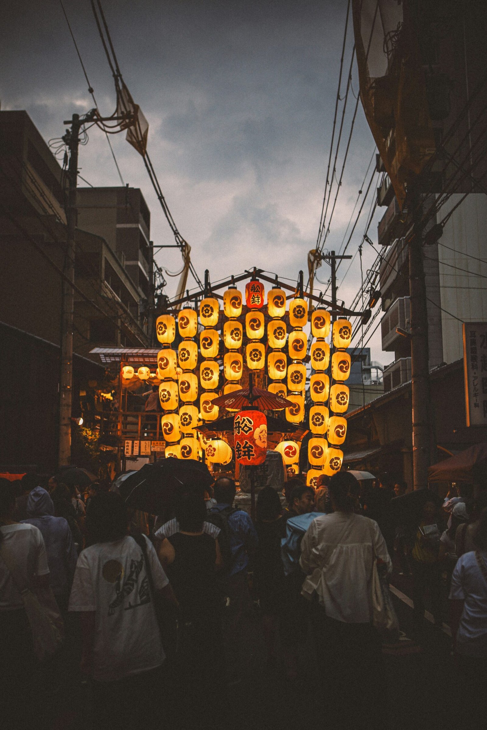 A group of people walking down a street next to tall buildings
